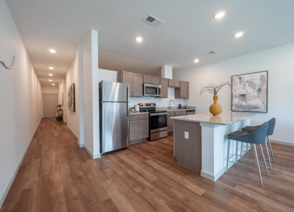 a kitchen with stainless steel appliances and a bar with stools at The Row on Merchant Apartments, Springdale, Ohio