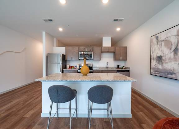 A kitchen with a bar and two chairs.at The Row on Merchant Apartments, Springdale, OH