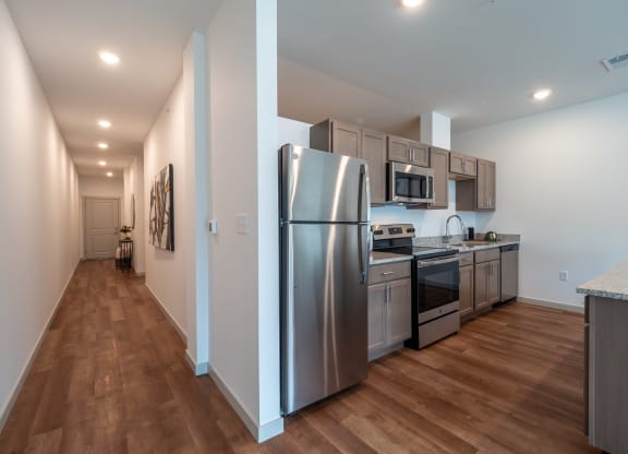 a kitchen with stainless steel appliances and wooden floors at The Row on Merchant Apartments, Springdale