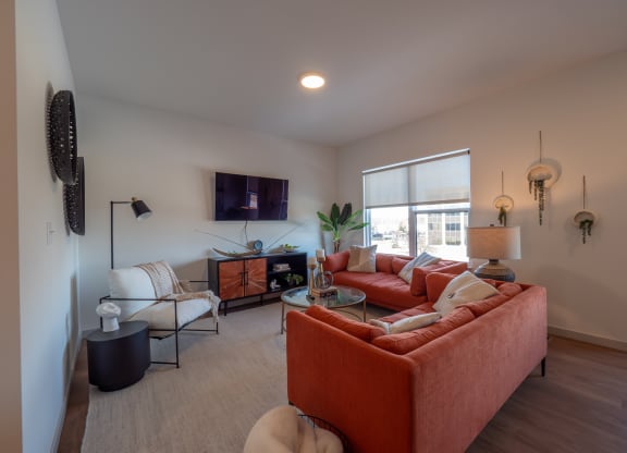 a living room with couches and chairs and a tv at The Row on Merchant Apartments, Ohio