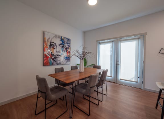 a dining room with a wooden table and chairs and a painting on the wall at The Row on Merchant Apartments, Springdale, Ohio