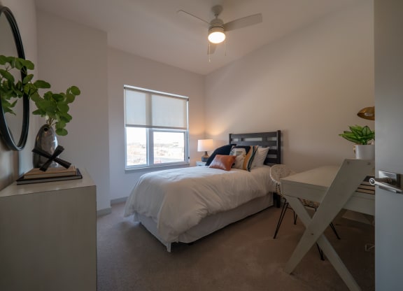 a bedroom with a bed and a desk and a ceiling fan at The Row on Merchant Apartments, Springdale, 45246