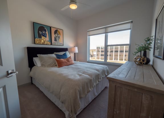 a bedroom with a bed and a large window at The Row on Merchant Apartments, Springdale, OH, 45246