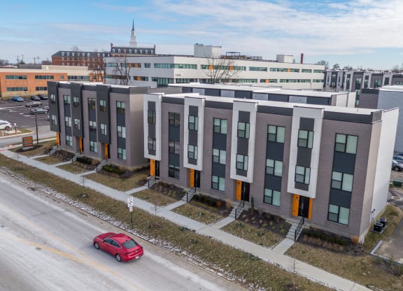 an aerial view of a building with a red car in front of it at The Row on Merchant Apartments, Springdale, 45246
