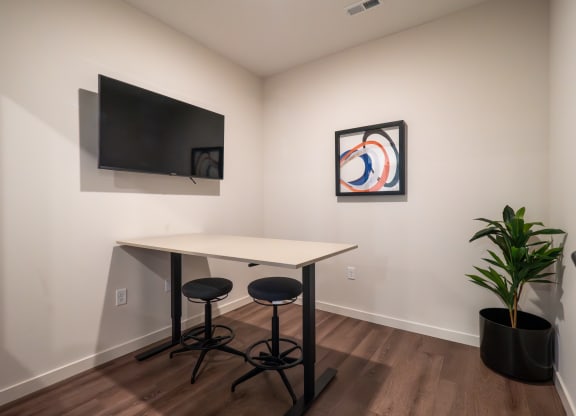 a small desk in a room with a tv and a plant at The Row on Merchant Apartments, Springdale
