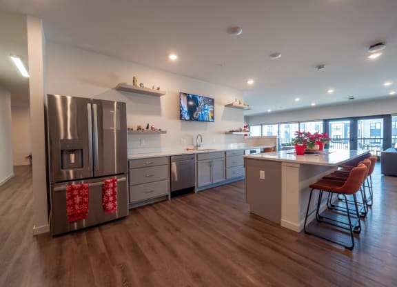 a large kitchen with stainless steel appliances and a bar with stools at The Row on Merchant Apartments, Springdale