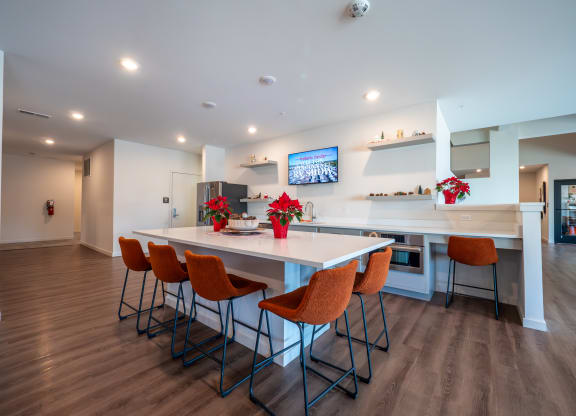 a kitchen with a white counter top and orange chairs at The Row on Merchant Apartments, Springdale, Ohio