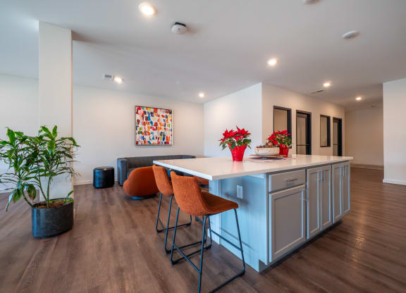 a kitchen with an island and stools in a living room with a couch at The Row on Merchant Apartments, Ohio