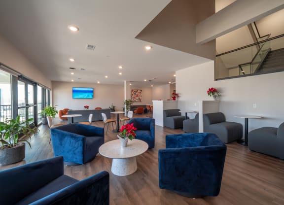 a living room with blue couches and chairs and a table at The Row on Merchant Apartments, Springdale, 45246