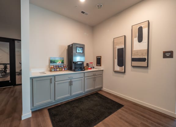 a room with a counter with a television and paintings on the wall at The Row on Merchant Apartments, Springdale, OH