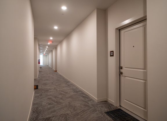 a hallway with white walls and a white door at The Row on Merchant Apartments, Springdale, OH