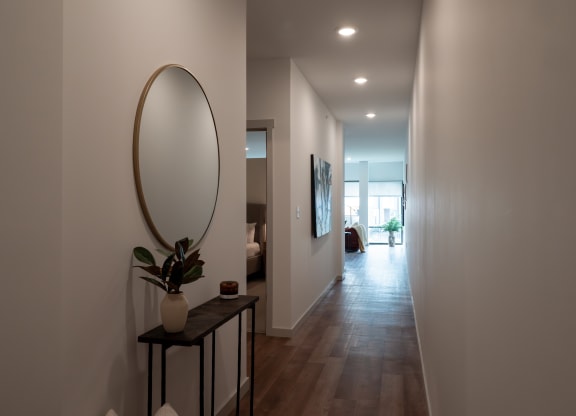 a hallway with a mirror and a table with a plant at The Row on Merchant Apartments, Ohio, 45246