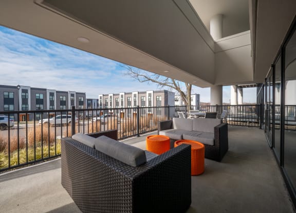 a balcony with couches and orange tables and a building in the background at The Row on Merchant Apartments, Ohio, 45246