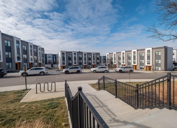 a row of apartment buildings on a city street with cars at The Row on Merchant Apartments, Springdale, OH, 45246