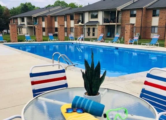 our apartments have a pool and a patio with chairs and a table