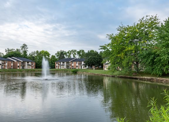a pond with a fountain in front of a row of houses