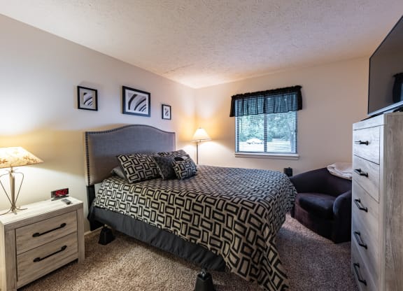 a bedroom with a bed and a dresser and a window