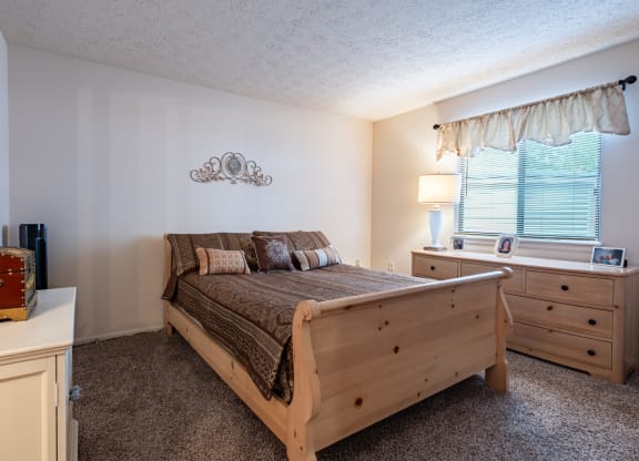 a bedroom with a bed and dresser and a window
