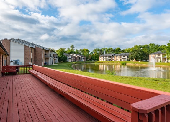 a picnic bench on a deck next to a pond