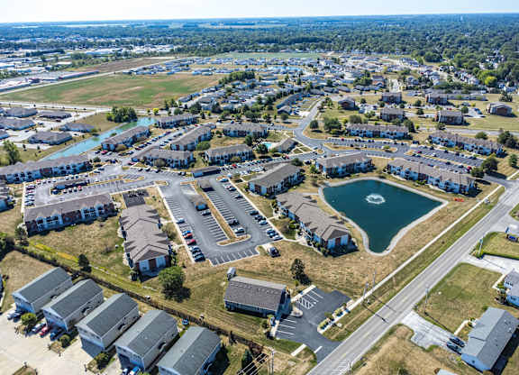 A bird's eye view of a residential area with houses, a lake, and a parking lot.