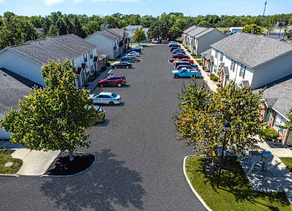 A parking lot with cars and houses in the background.