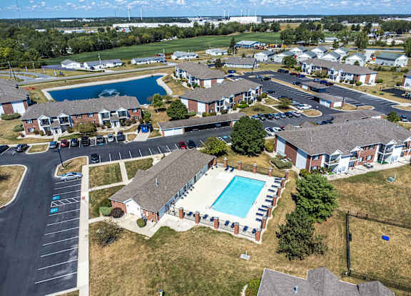 A bird's eye view of a residential area with houses, swimming pools, and a parking lot.