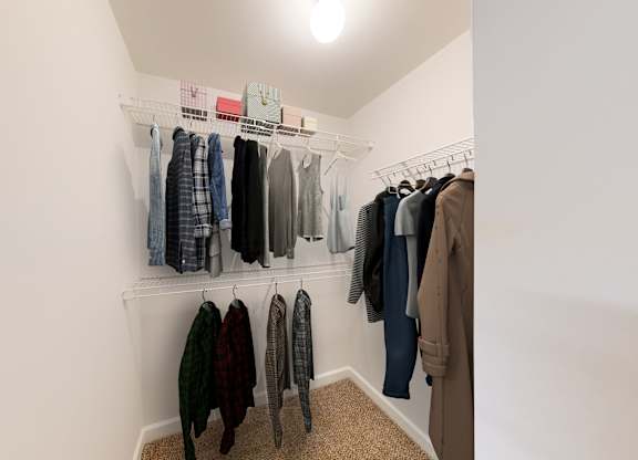 a walk in closet in a bedroom with white walls and a ceiling with a light