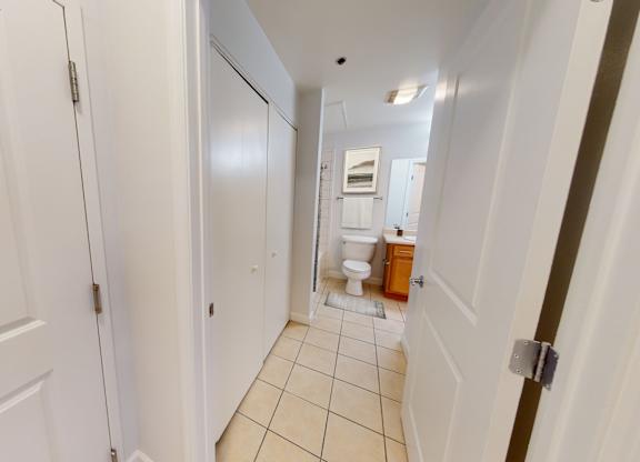a hallway with two doors and a bathroom in the background