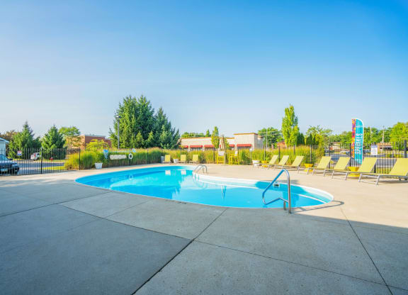 a swimming pool with yellow chairs around it and a blue sky