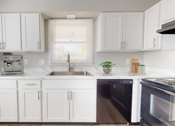 a white kitchen with white cabinets and black appliances and a window at Stonebrook of Franklin, Franklin, IN, 46131