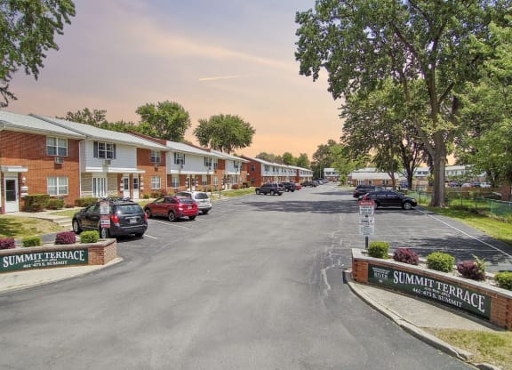 a street with houses and cars parked in a parking lot