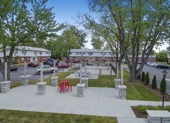 a park area with tables and chairs in front of a parking lot
