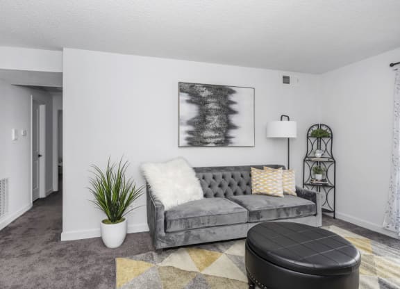 Living room with a gray couch and a black ottoman at Tall Timber Apartments, Ohio, 45241