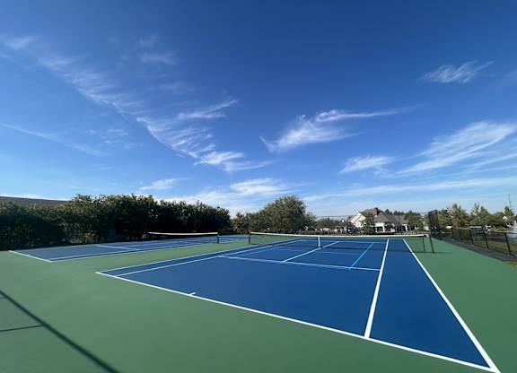 A tennis court with blue and green colors under a clear sky.