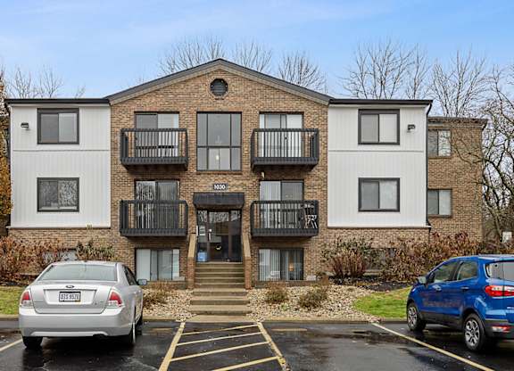 A car is parked in front of a building with a balcony. at The Reserve at Grand Valley Apartments, Milford, Ohio