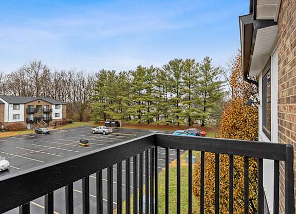 A parking lot with cars and a building in the background at The Reserve at Grand Valley Apartments, Milford, OH