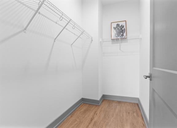 A white hallway with a wooden floor and a white door.