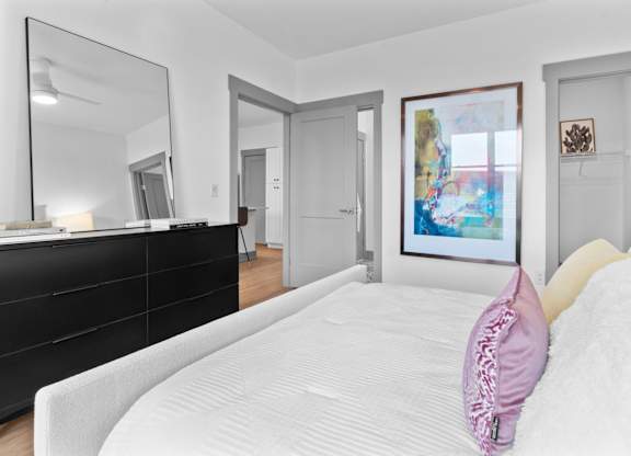 A bedroom with a large bed and a painting on the wall.