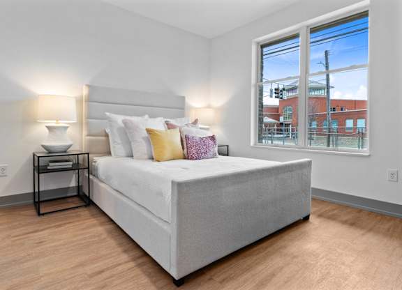 A bedroom with a large bed and a window overlooking a cityscape.