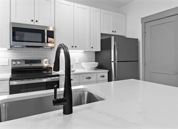 A kitchen with a sink, stove, and refrigerator.