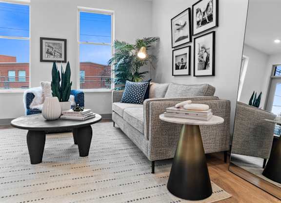 A living room with a grey couch, a coffee table, and a large window.