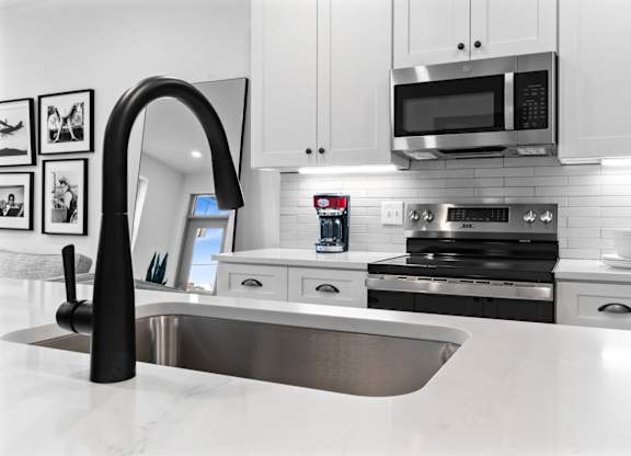 A modern kitchen with a stainless steel sink and white cabinets.