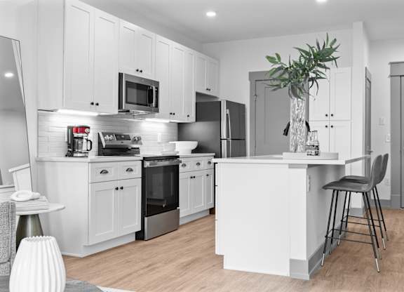 A modern kitchen with white cabinets and stainless steel appliances.
