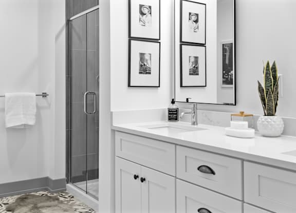 A bathroom with a white sink, a mirror, and a glass shower door.