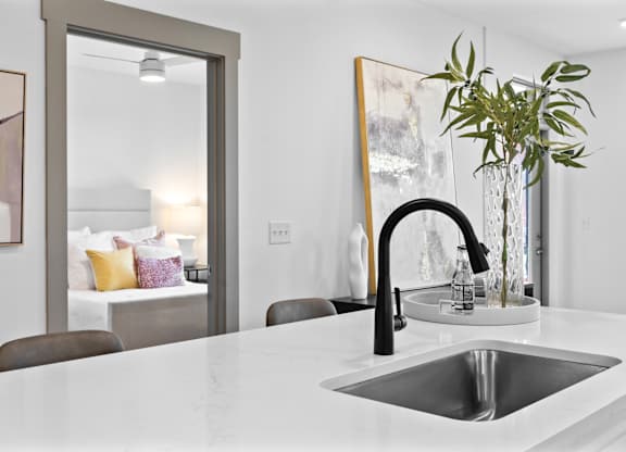 A modern kitchen with a white countertop and a black faucet.