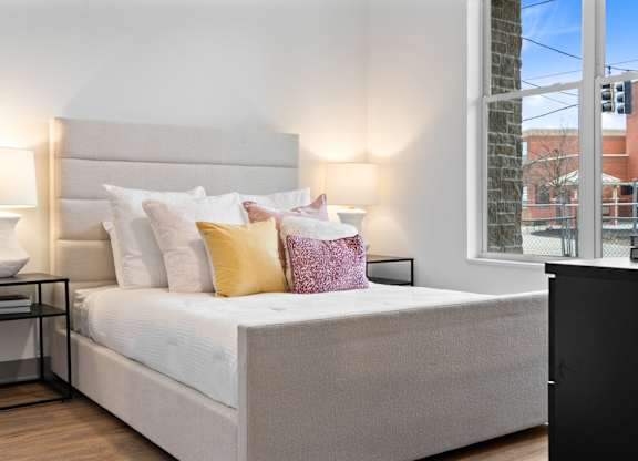 A bed with a white headboard and a white bedspread with multiple pillows.