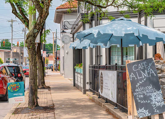 A blue umbrella is on the sidewalk in front of a cafe. at The Ridge Apartments, Cincinnati, Ohio