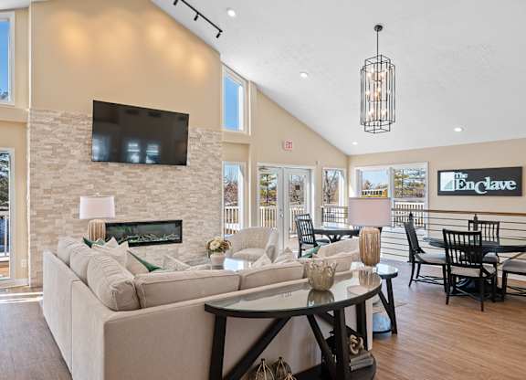 A living room with a white couch and a flat screen TV mounted on the wall at Enclave, Beavercreek, OH