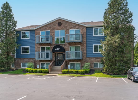an apartment building with a parking lot in front of it