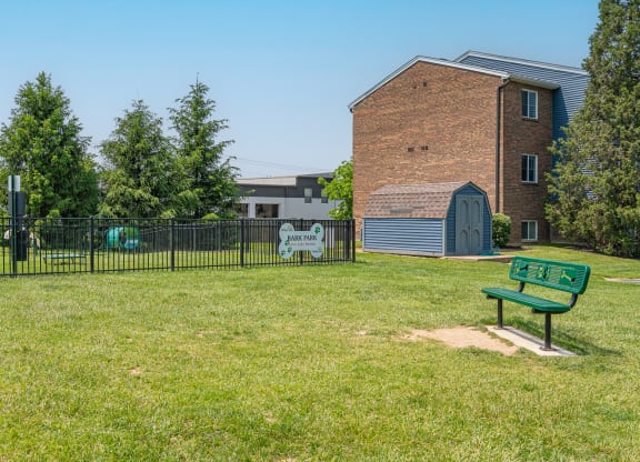 a park with a bench in front of a fence and a building